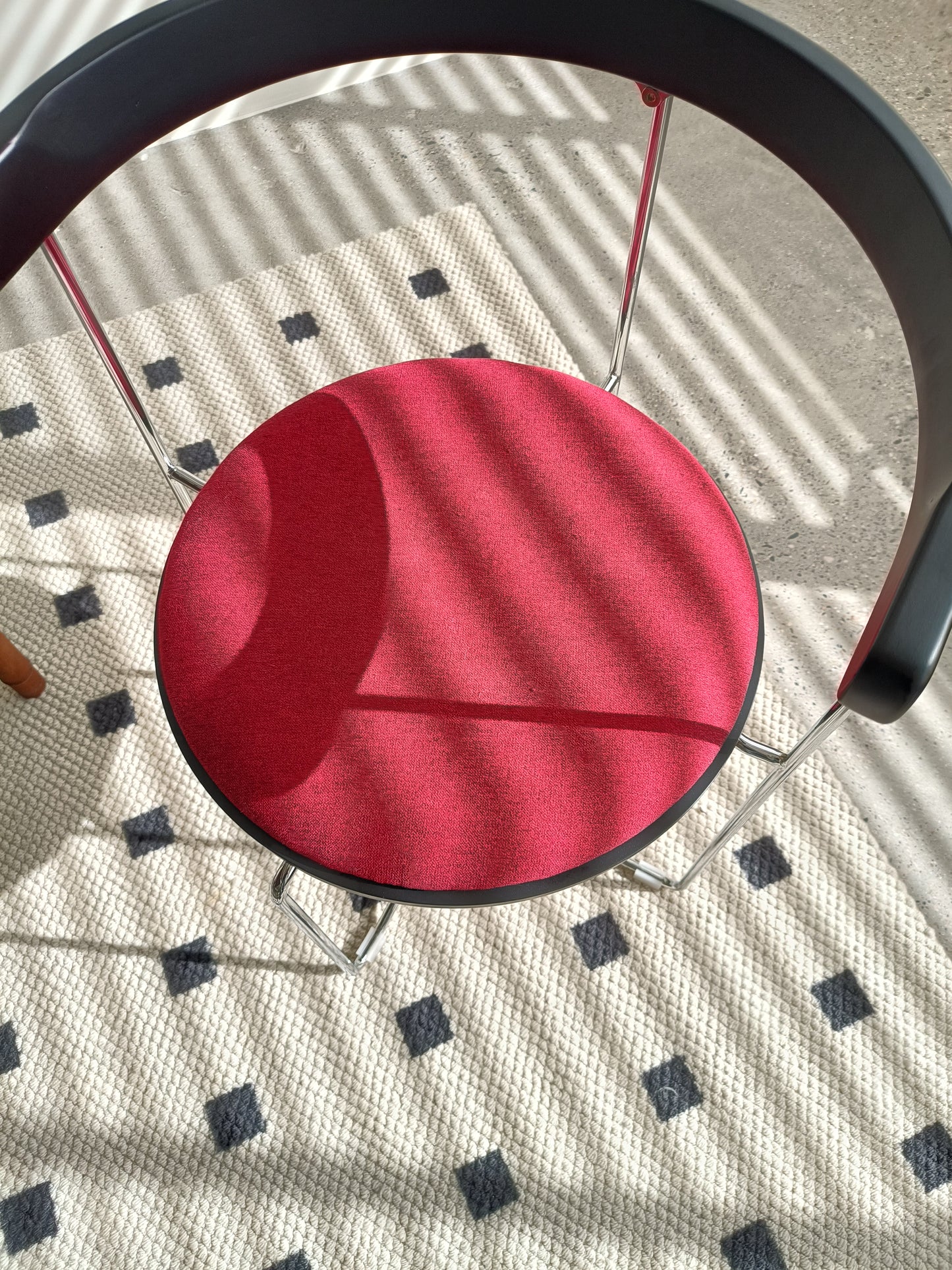Red fabric dining chair with a black backrest and chrome legs
