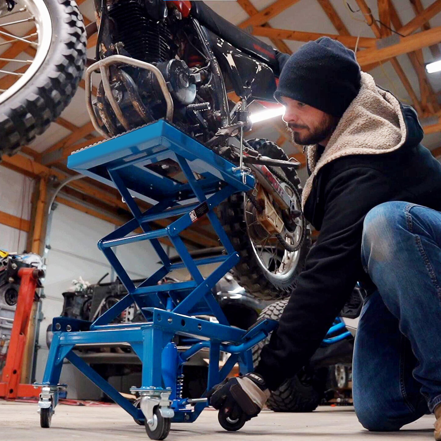 Blue motorcycle lift with a person adjusting a bike heavy duty garage equipment