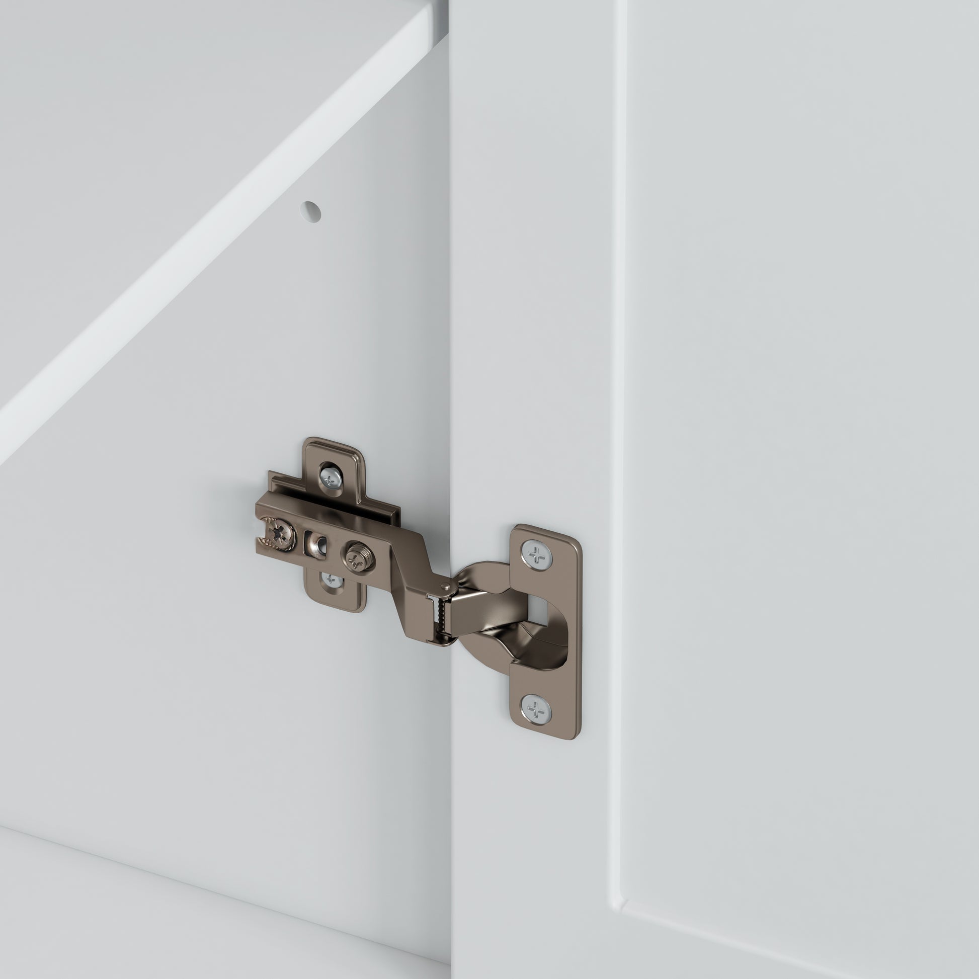 Closeup of a polished nickel cabinet hinge with visible screws on a white cabinet door