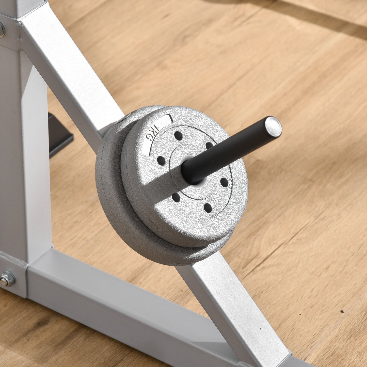 Silver weight plates with KG marking on a chrome barbell sleeve attached to gym equipment