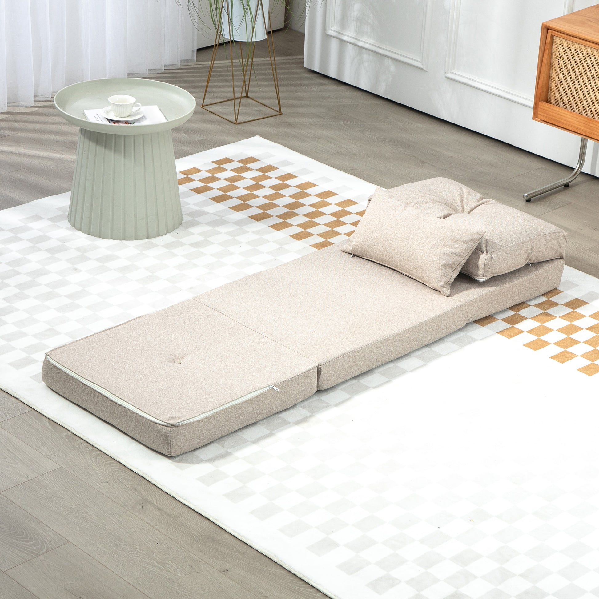 Beige upholstered convertible sofa bed with two plush pillows