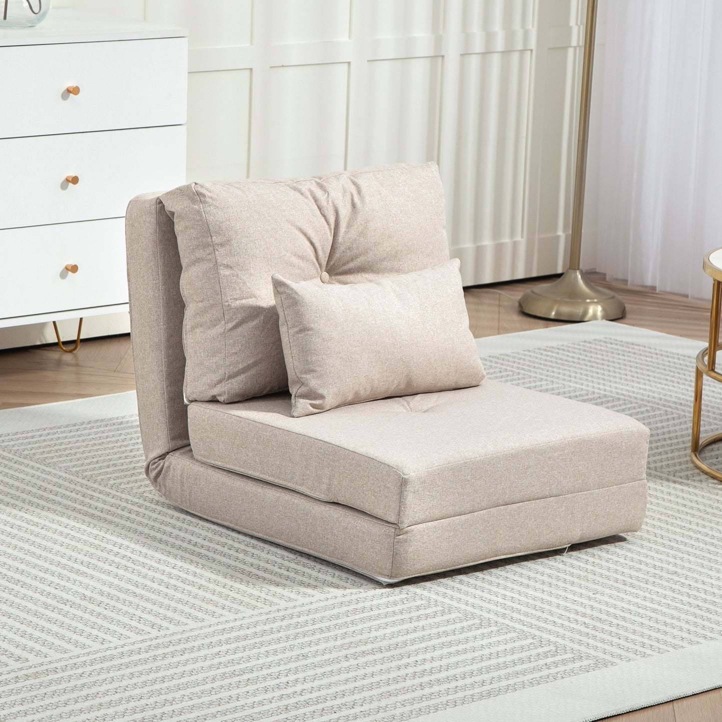 Beige fabric folding chair with tufted back and accent pillow on rug