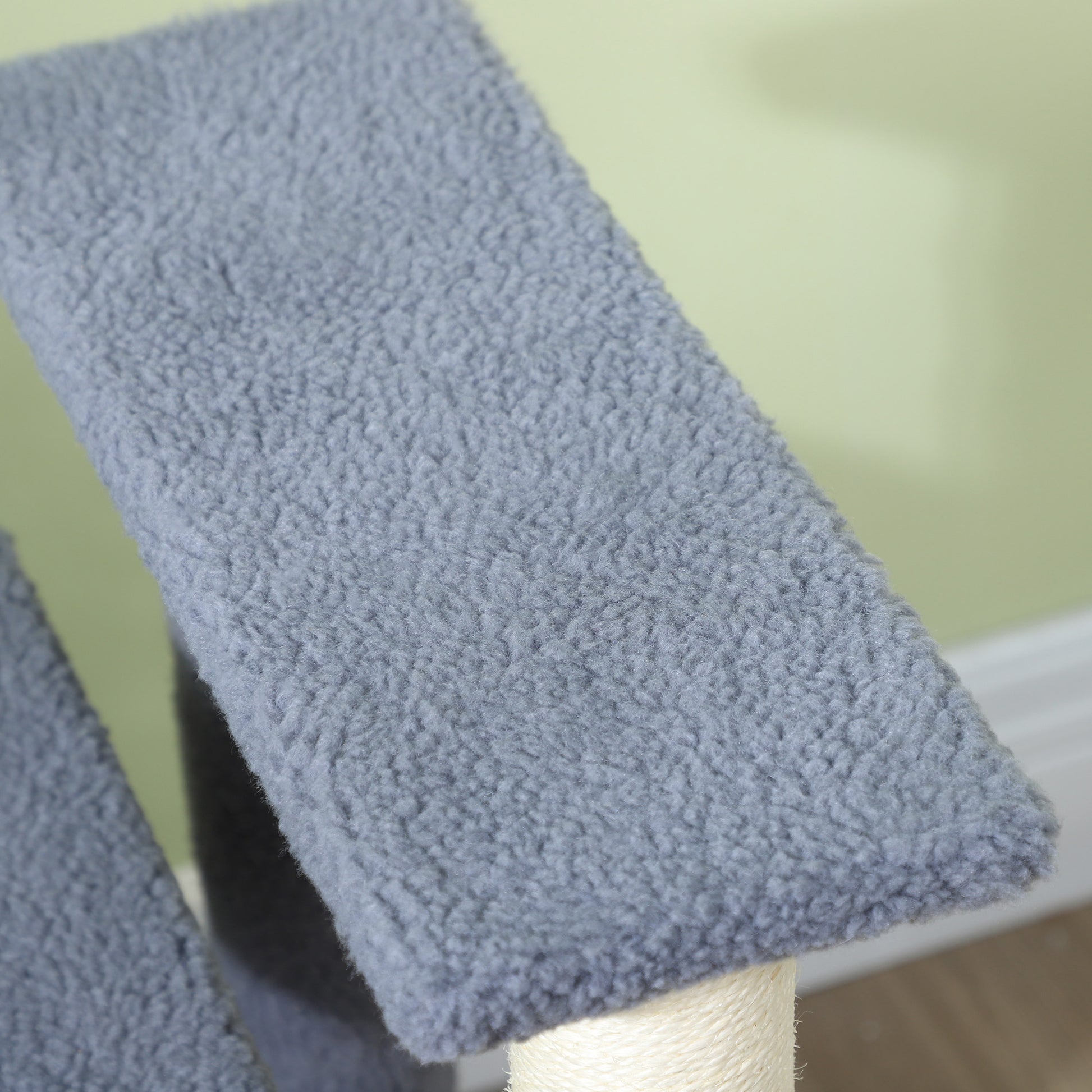 Closeup of a grey fluffy fabric platform on a cat tree scratching post