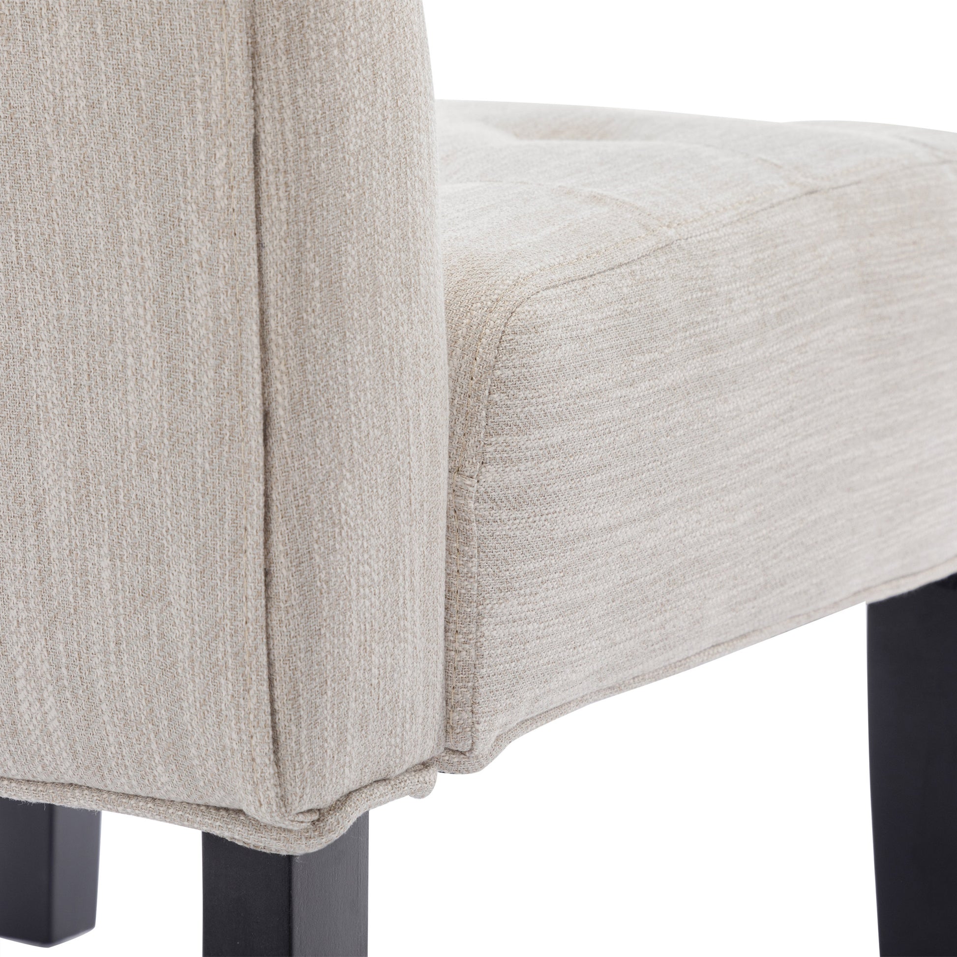 Closeup of a beige textured fabric armchair seat with subtle tufting modern design
