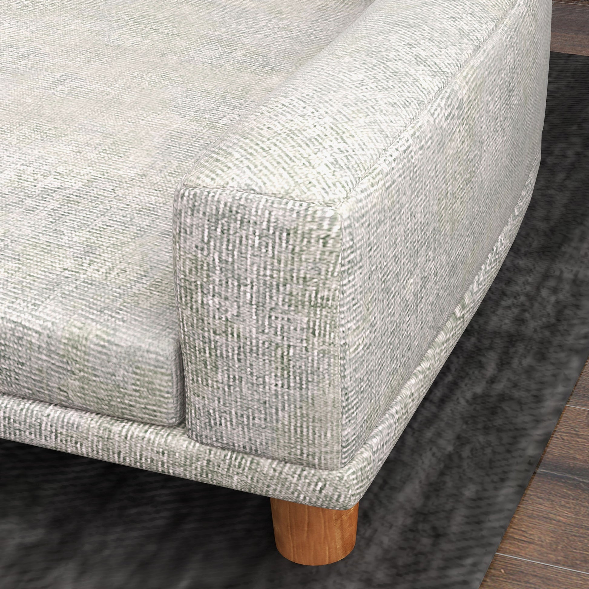 Closeup of a textured light gray sofa with a subtle green weave and wooden legs