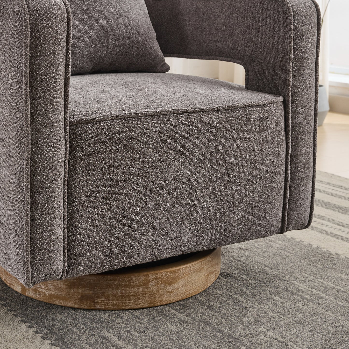 Closeup of a textured gray fabric armchair with a swiveling wooden base