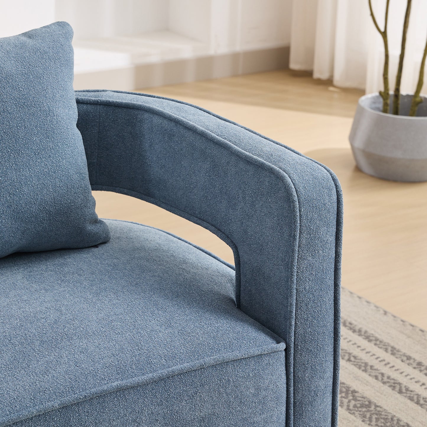 Closeup of a plush blue accent chair with textured fabric and supportive armrests