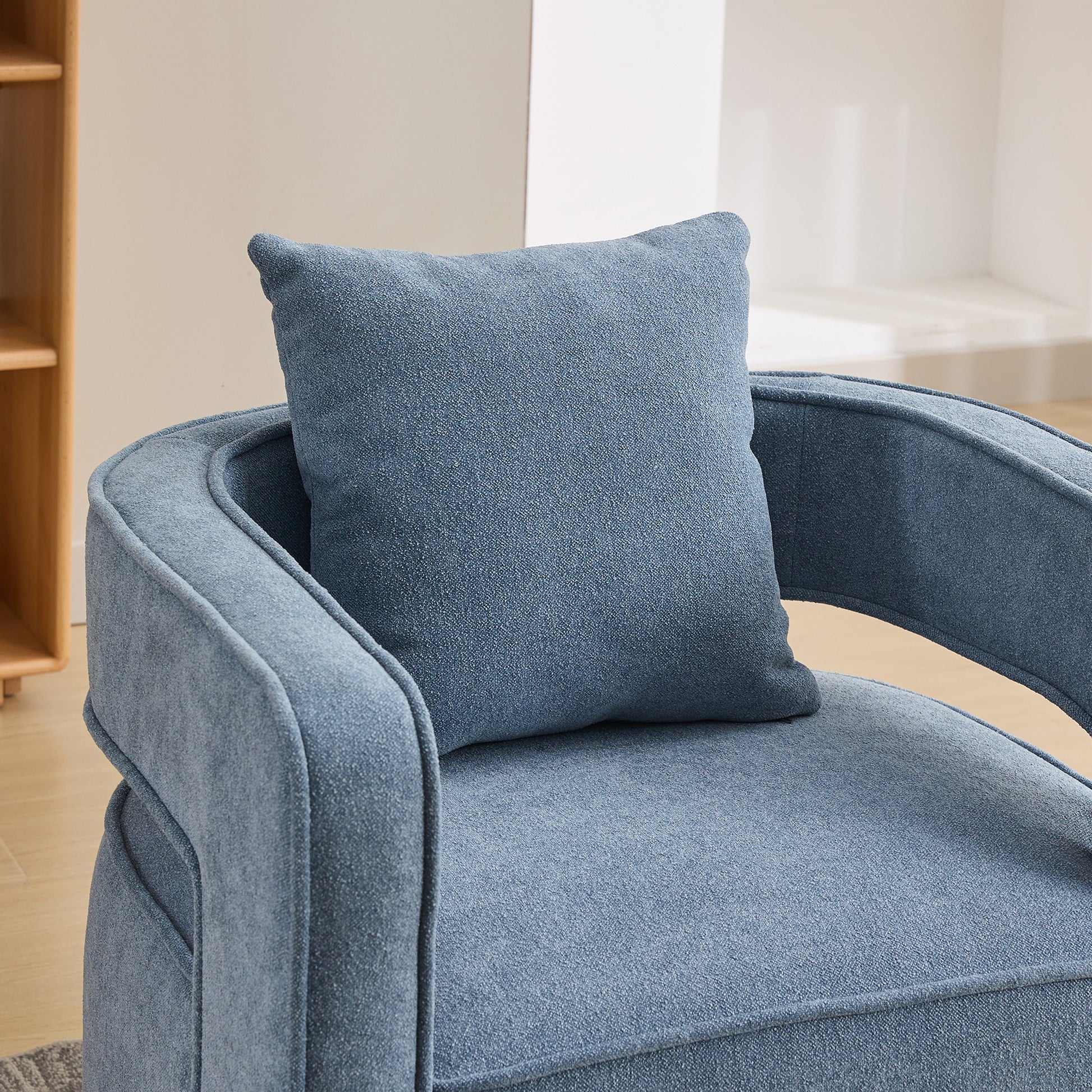 Closeup of a textured blue armchair with a matching lumbar pillow