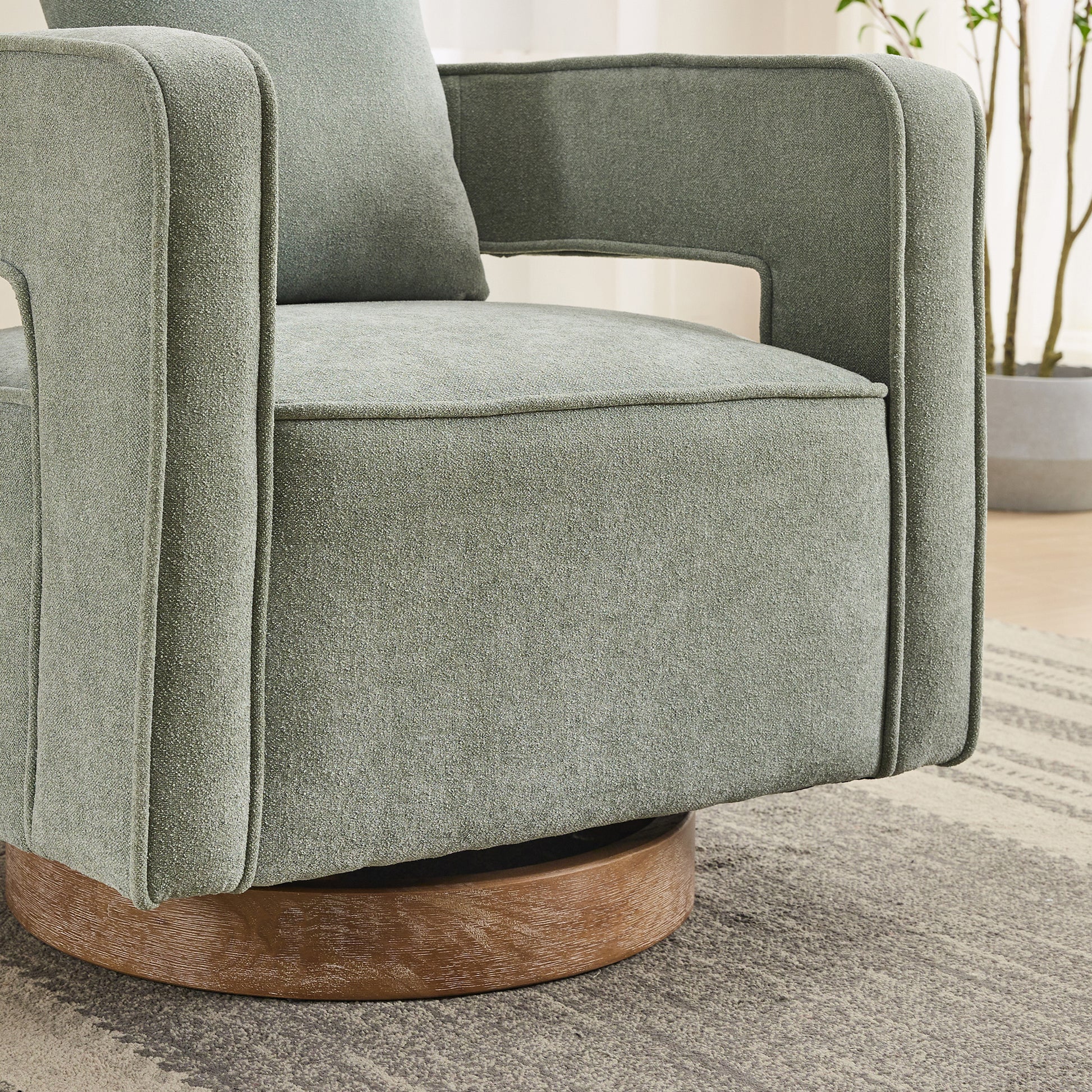Sage green fabric armchair with a wooden swivel base for modern living rooms