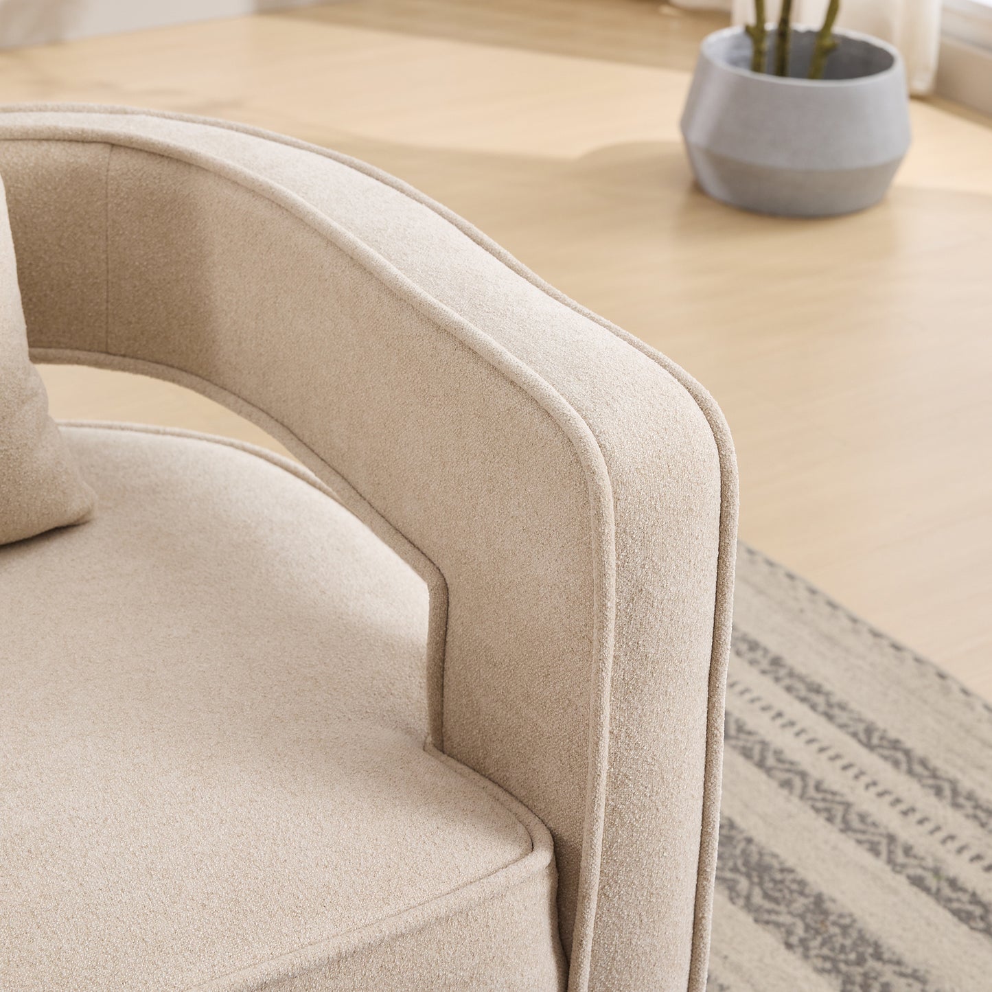 Closeup of a textured beige accent chair armrest emphasizing plush fabric and clean lines