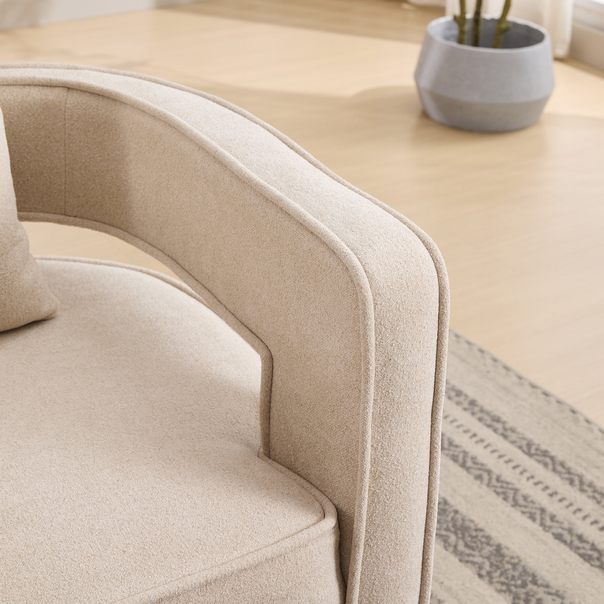 Closeup of a textured beige accent chair armrest emphasizing plush fabric and clean lines