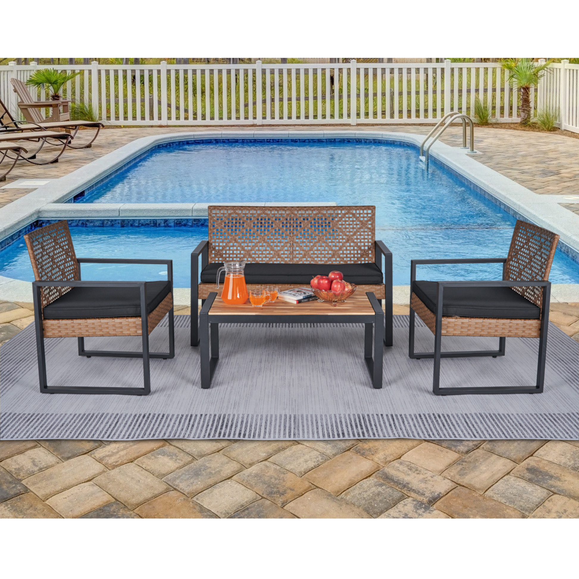 Wicker patio set with black cushions including two chairs a loveseat and a coffee table