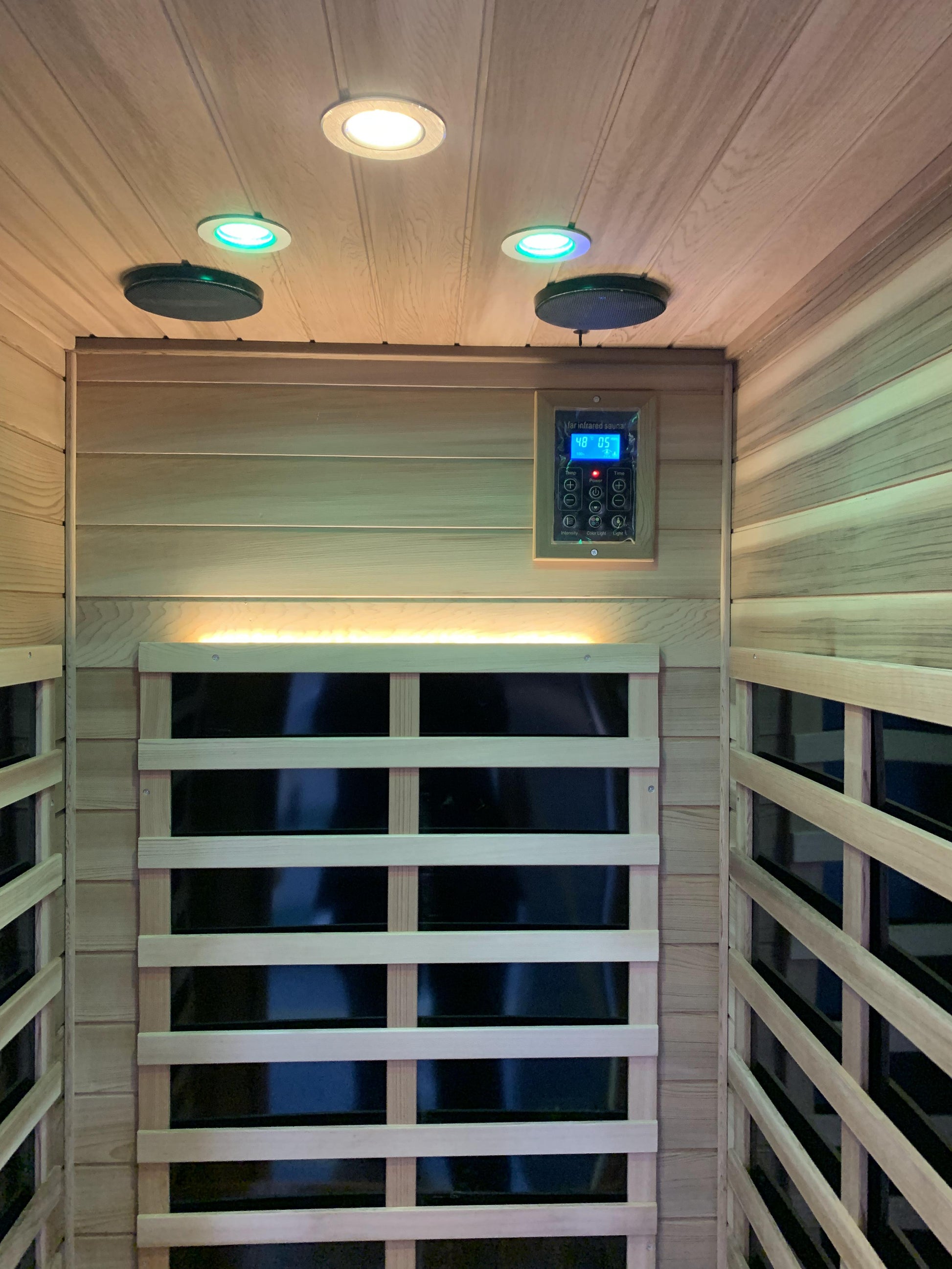 Interior view of a wooden sauna with LED lights and a digital control panel