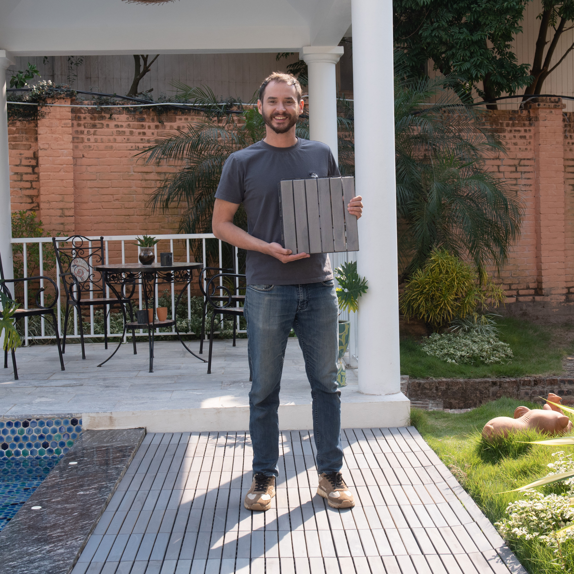 Dark grey composite deck tiles shown held by a man for patio flooring