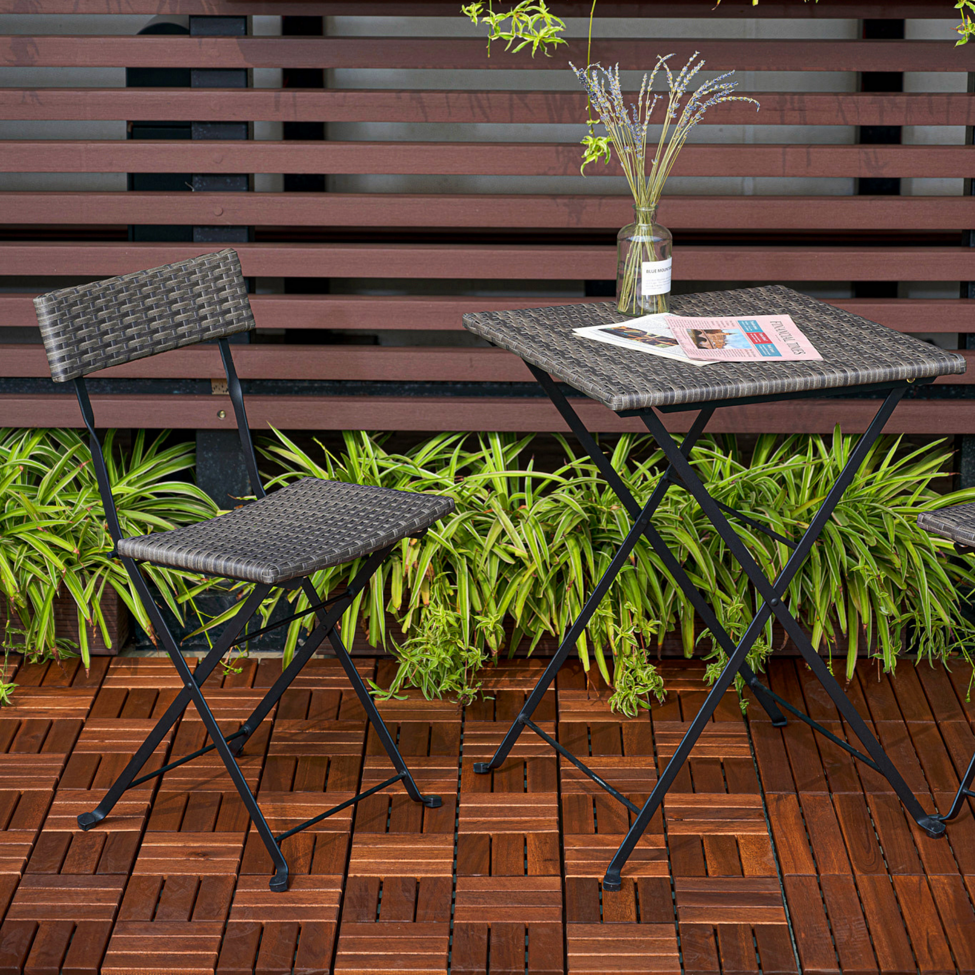 Gray rattan folding bistro chair with black metal frame on wooden deck