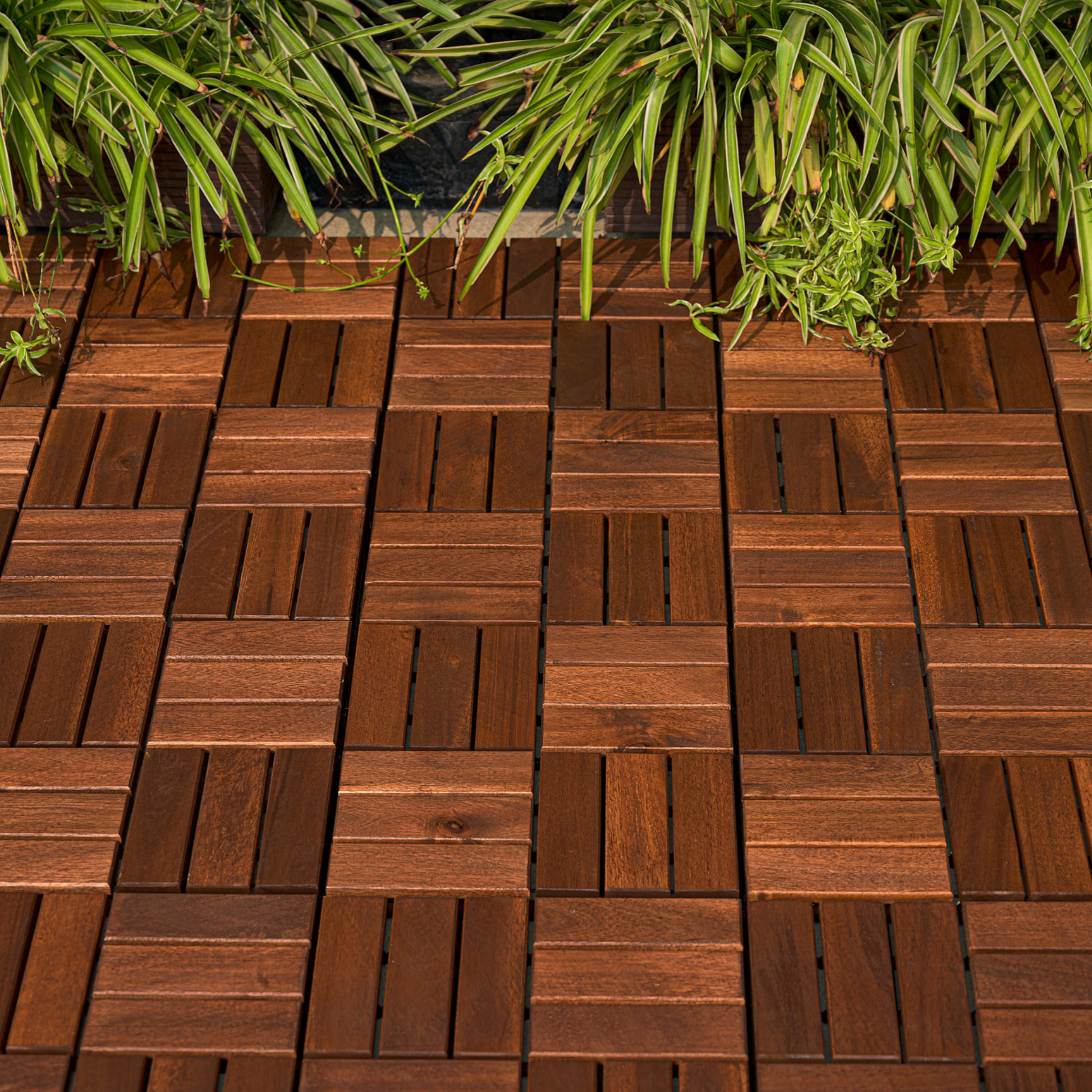 Rich brown hardwood deck tiles arranged in a geometric pattern with lush green foliage above