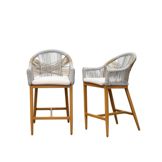 Two woven rattan outdoor bar stools with white cushions and wood legs
