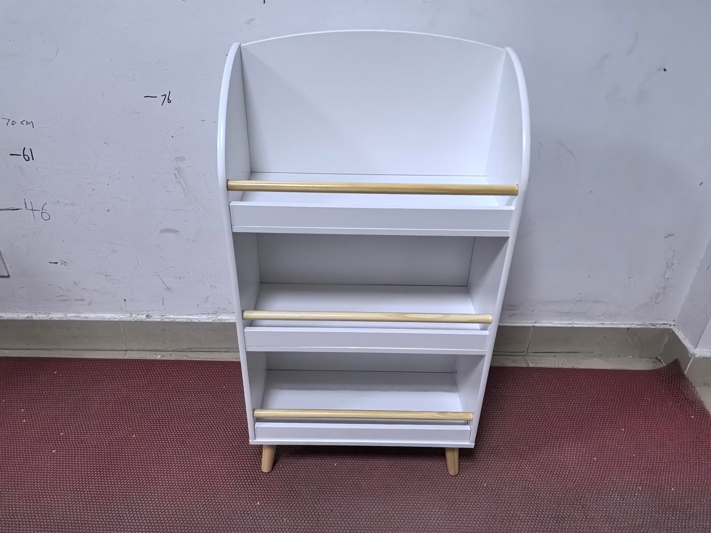 White wooden bookshelf with three shelves and wooden dowels for book support