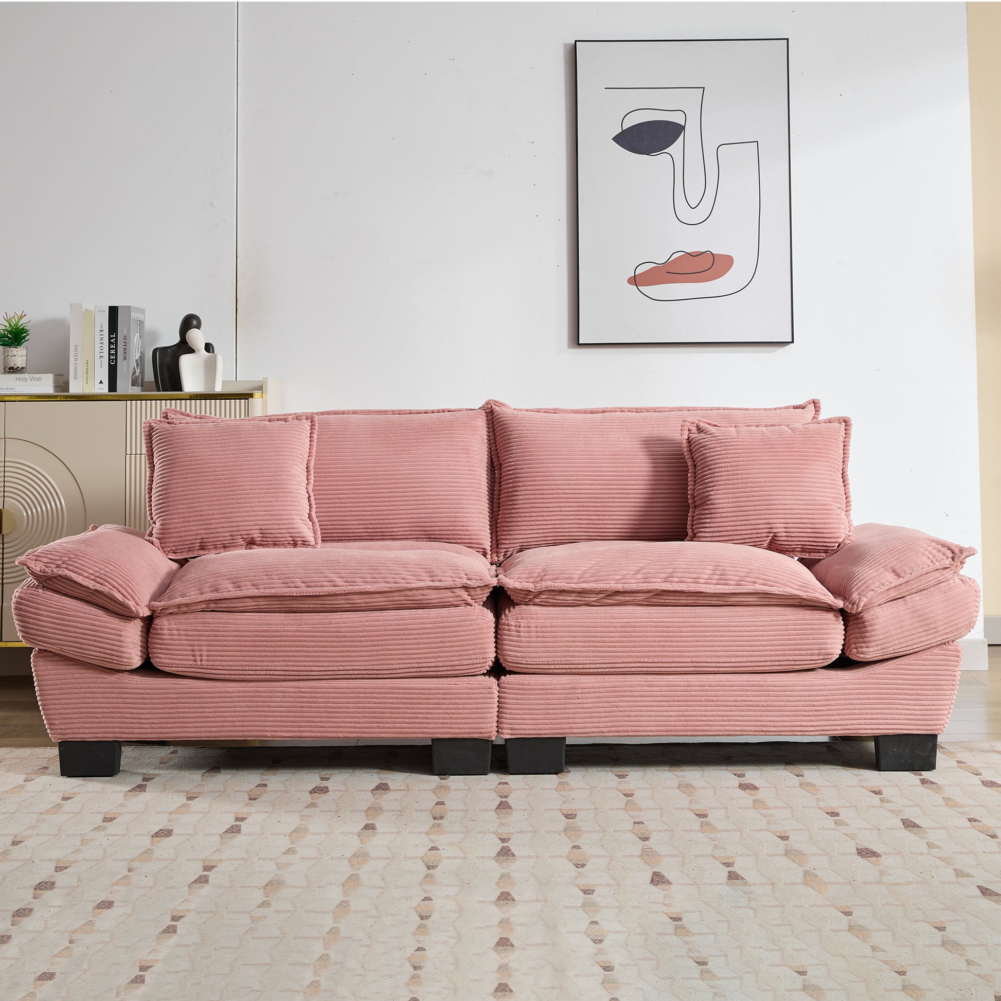 Plush pink corduroy sofa with two accent pillows ideal for a cozy living room