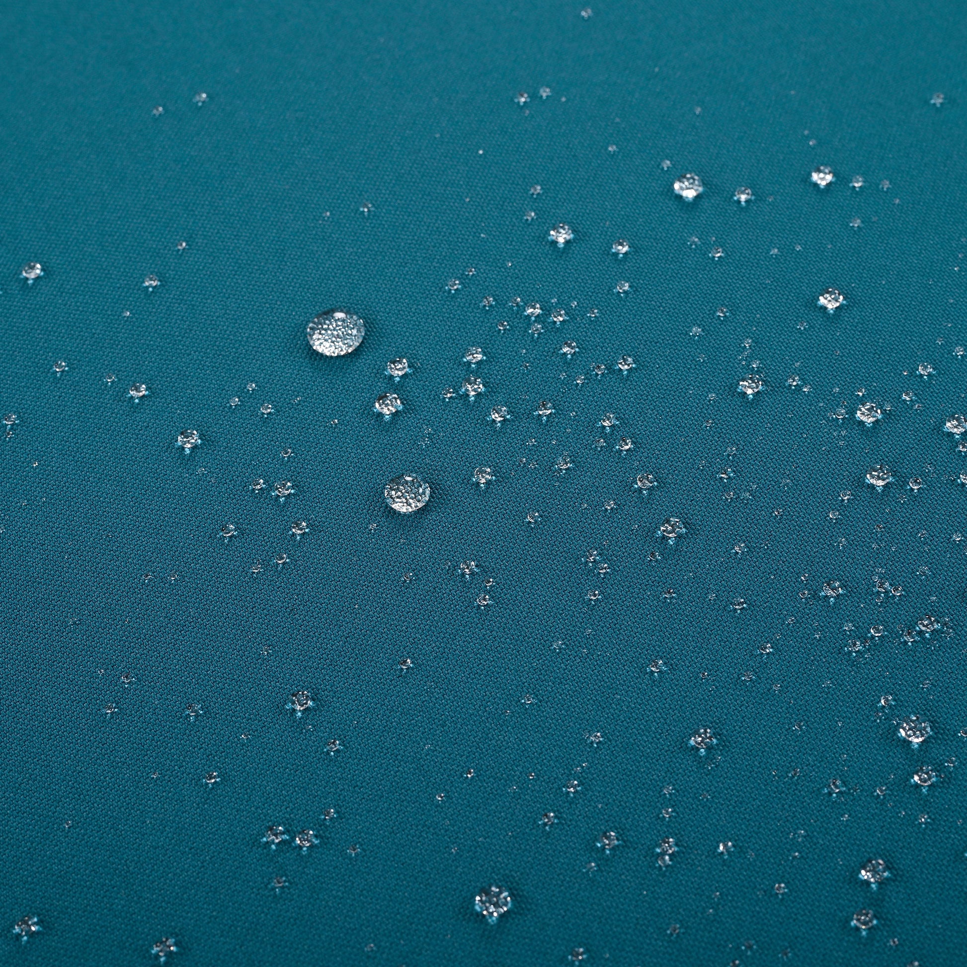 Teal fabric showing small water droplets beading on its waterproof surface