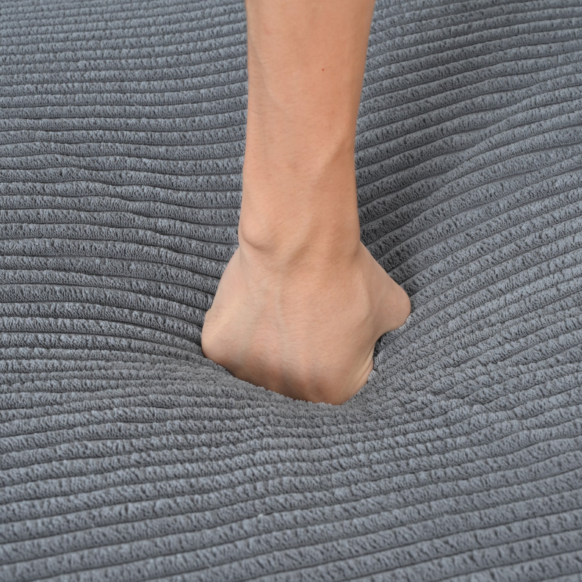Soft grey corduroy textured rug foot pressing into plush material