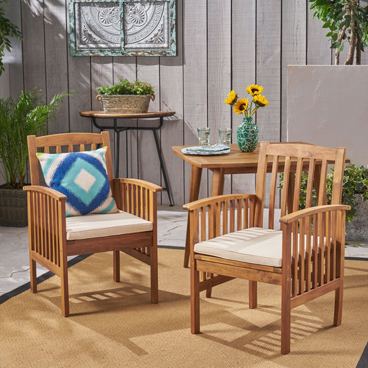 Two solid wood patio chairs with cream cushions and a blue zigzag pillow