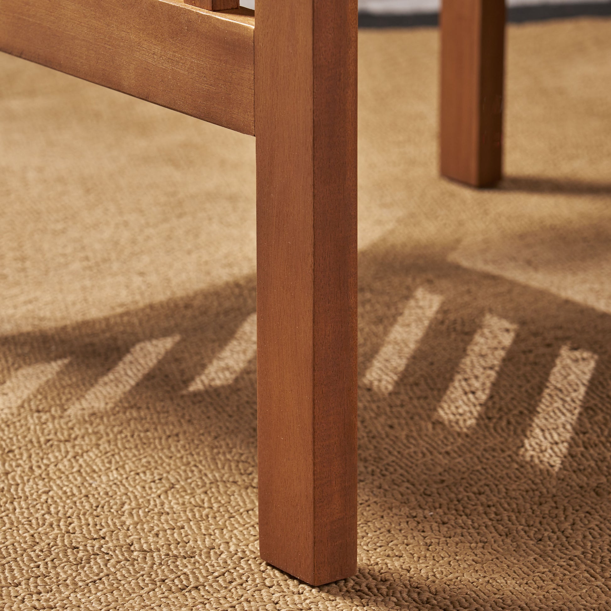 Closeup of a solid wood table leg with natural grain detail on a textured rug
