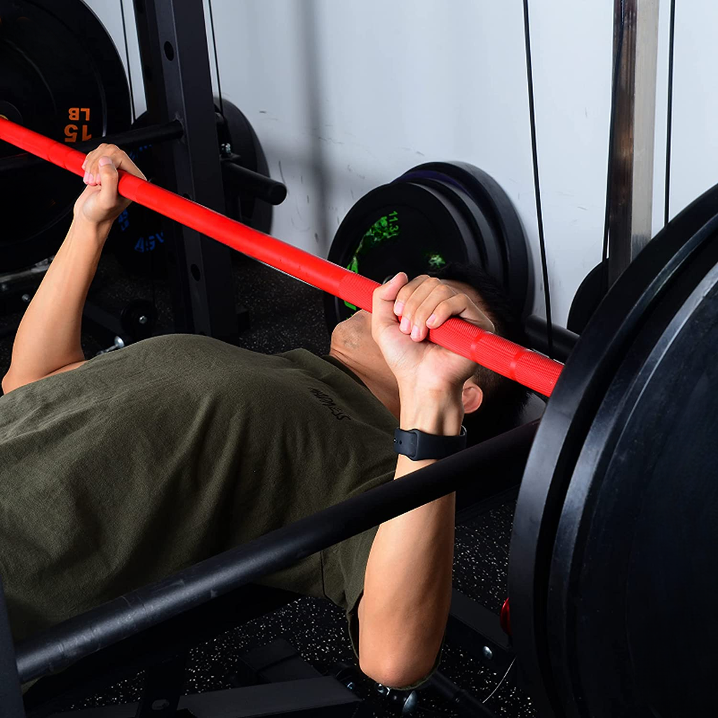 Man performing bench press with red barbell black weight plates