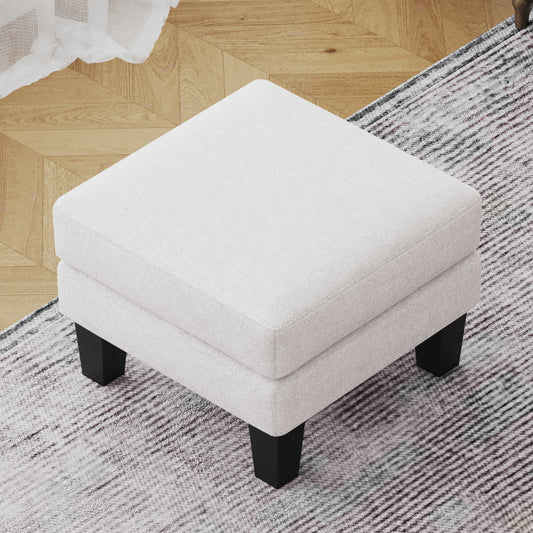 Square offwhite linen ottoman with tapered black legs on a patterned rug