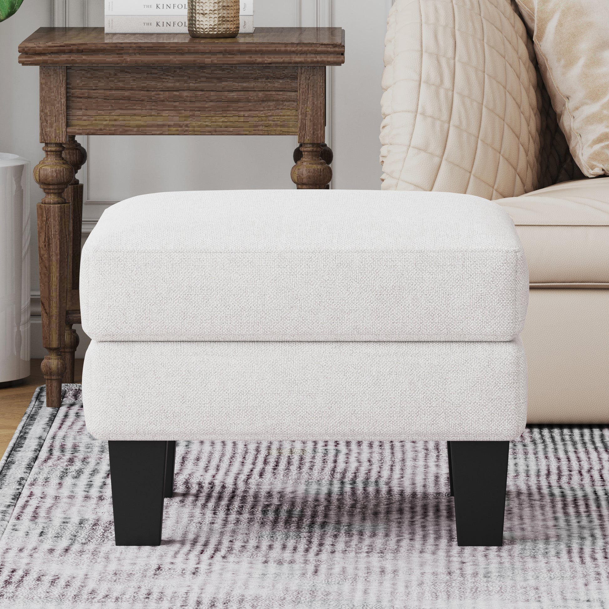 White upholstered ottoman with dark tapered legs and textured fabric perfect as a footrest