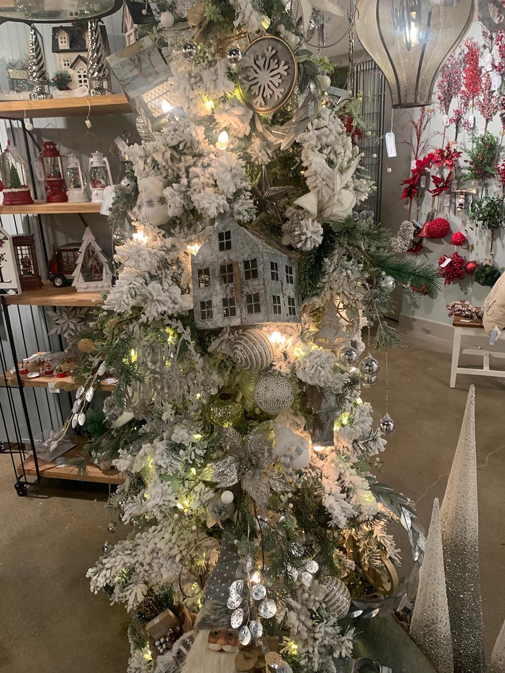 Flocked Christmas tree with white glitter garland and a metal house ornament