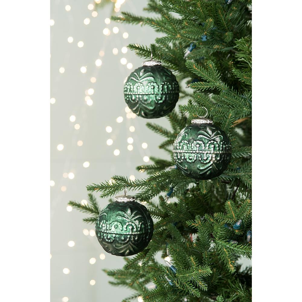 Emerald green ornate glass Christmas ornaments hanging on a decorated tree