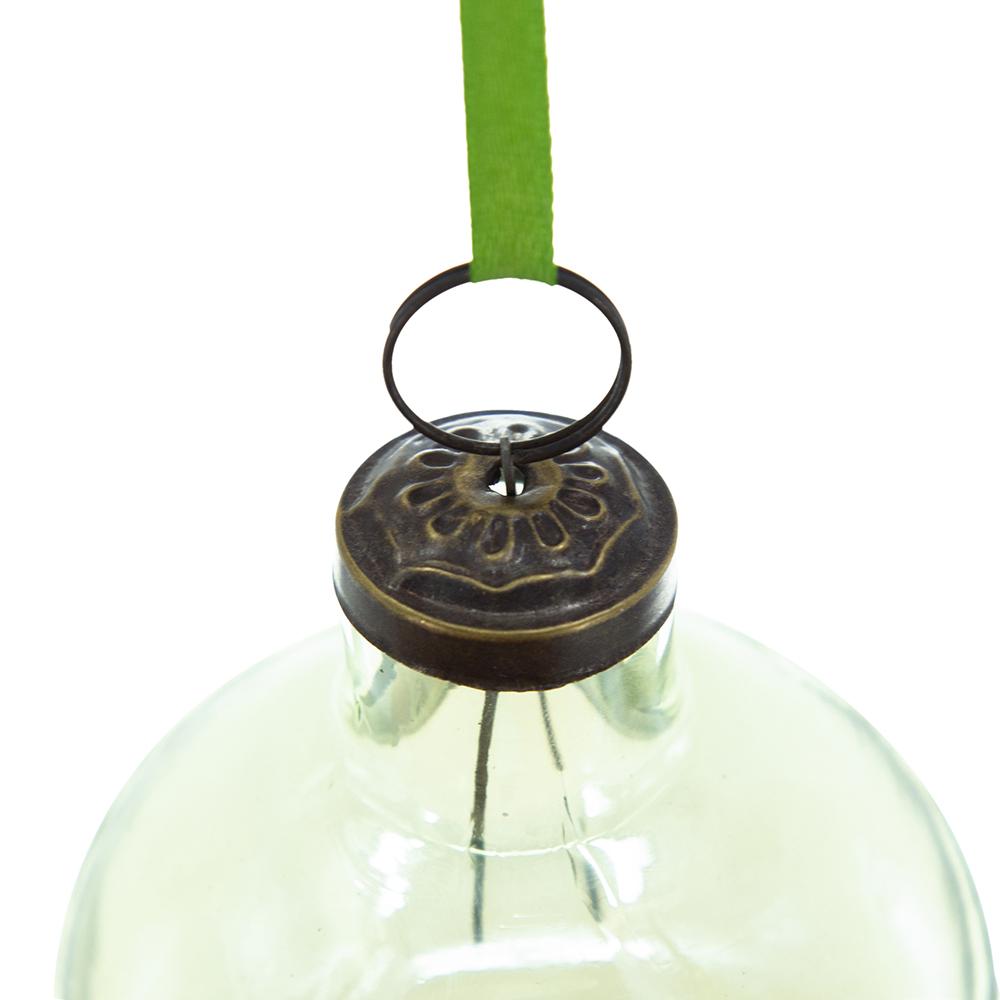 Antique brass finial on a pale green glass Christmas ornament with a green ribbon