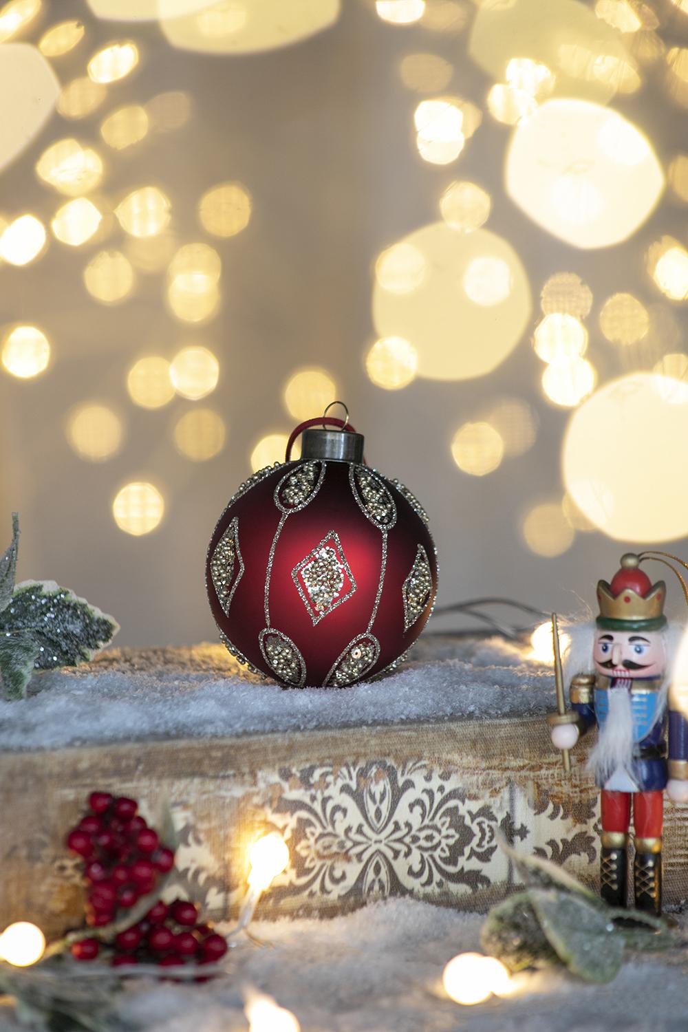 Deep red glass Christmas ornament with intricate silver beadwork and diamond patterns