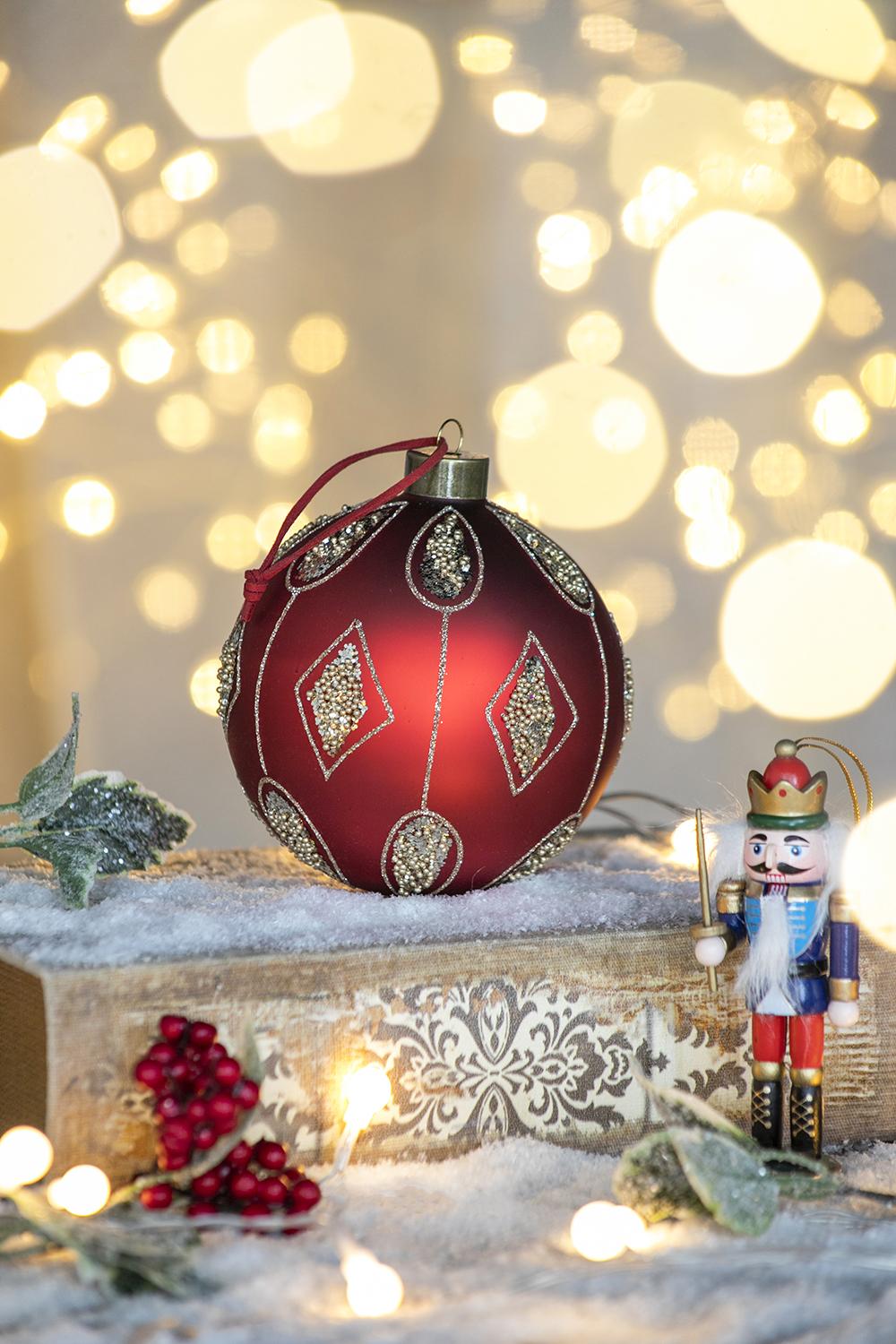 Red glass Christmas ornament with gold detailing and sparkling accents