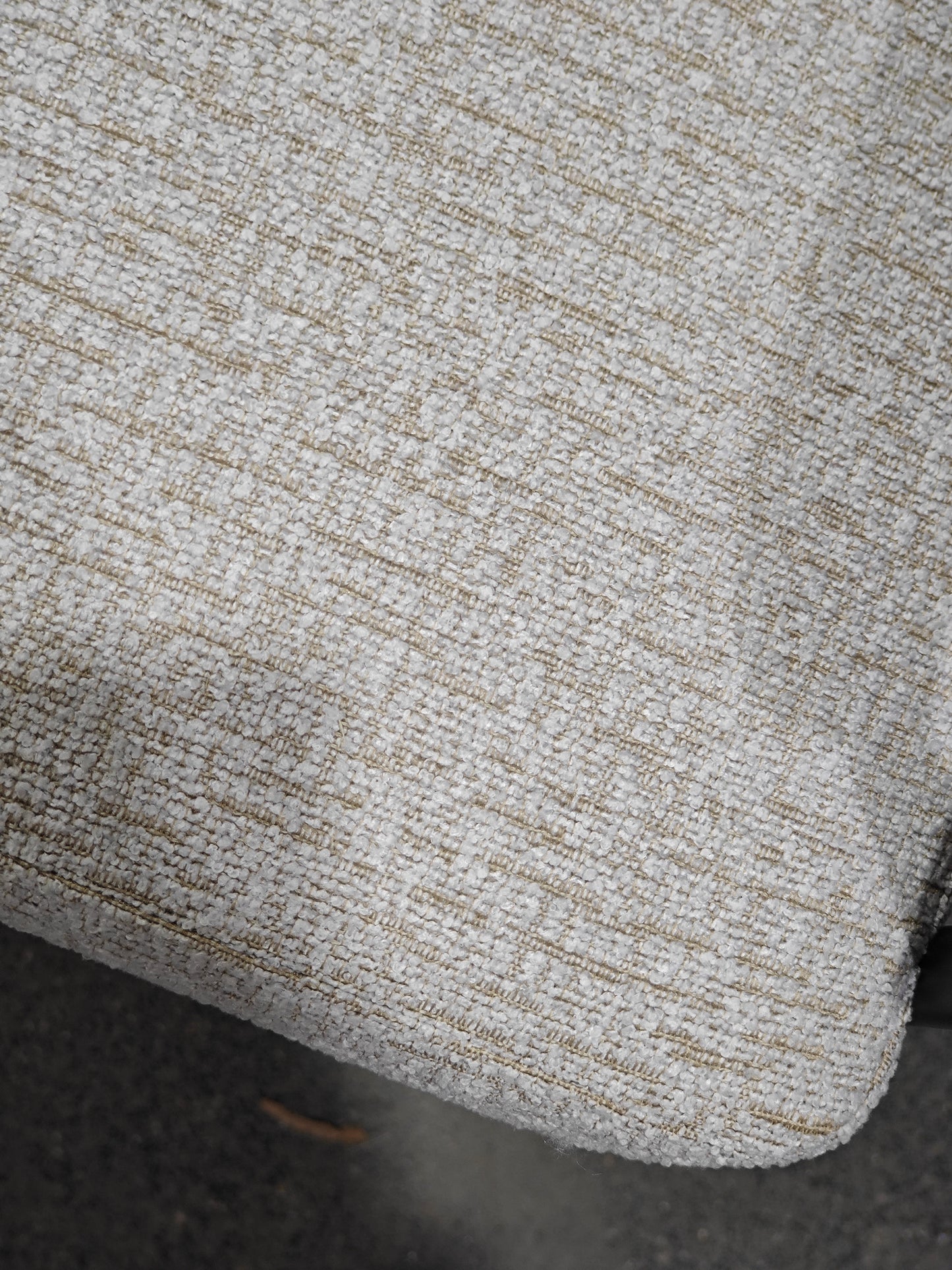 Closeup of light gray textured upholstery fabric with gold threads woven in for a sophisticated finish