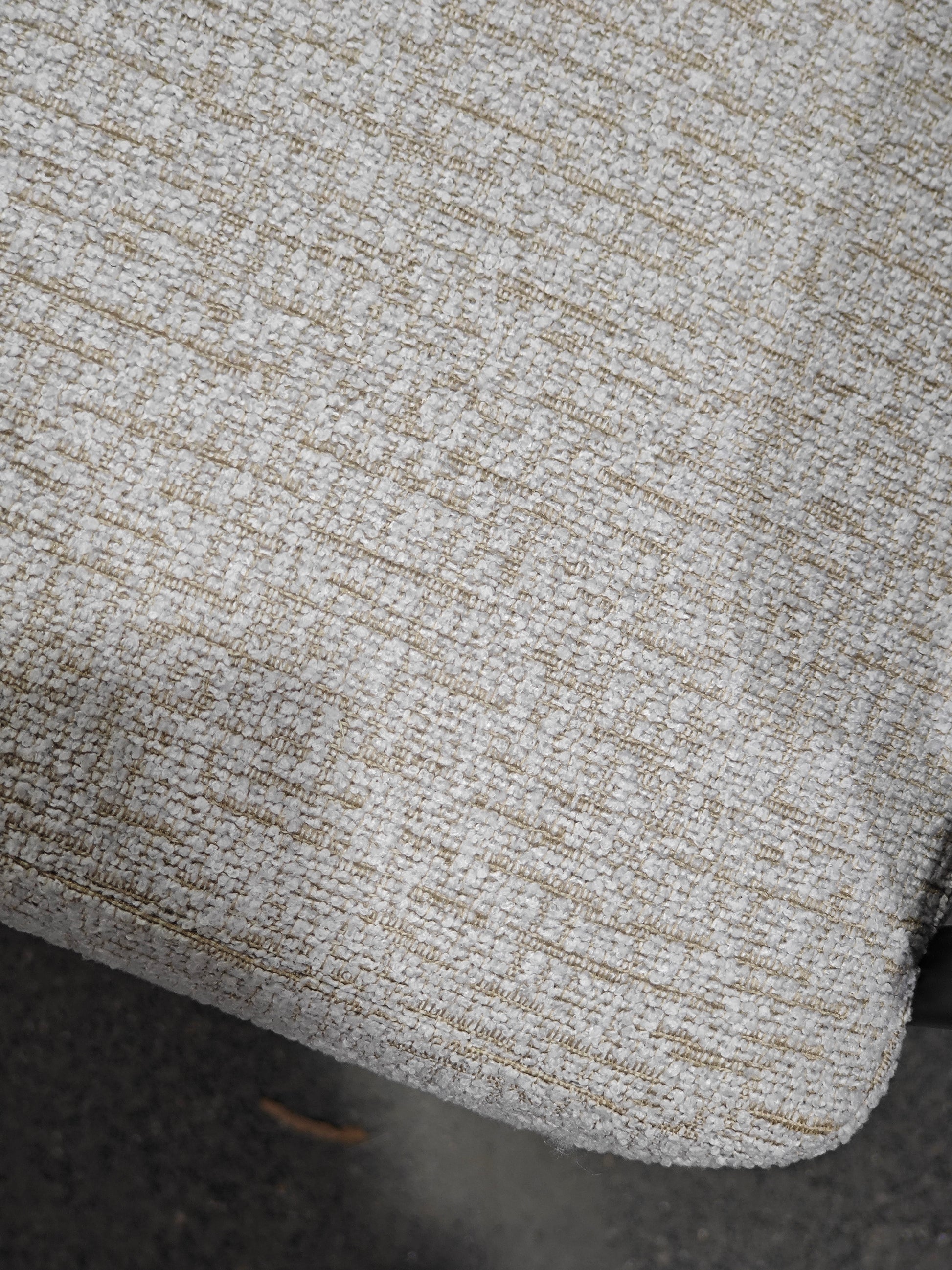 Closeup of light gray textured upholstery fabric with gold threads woven in for a sophisticated finish