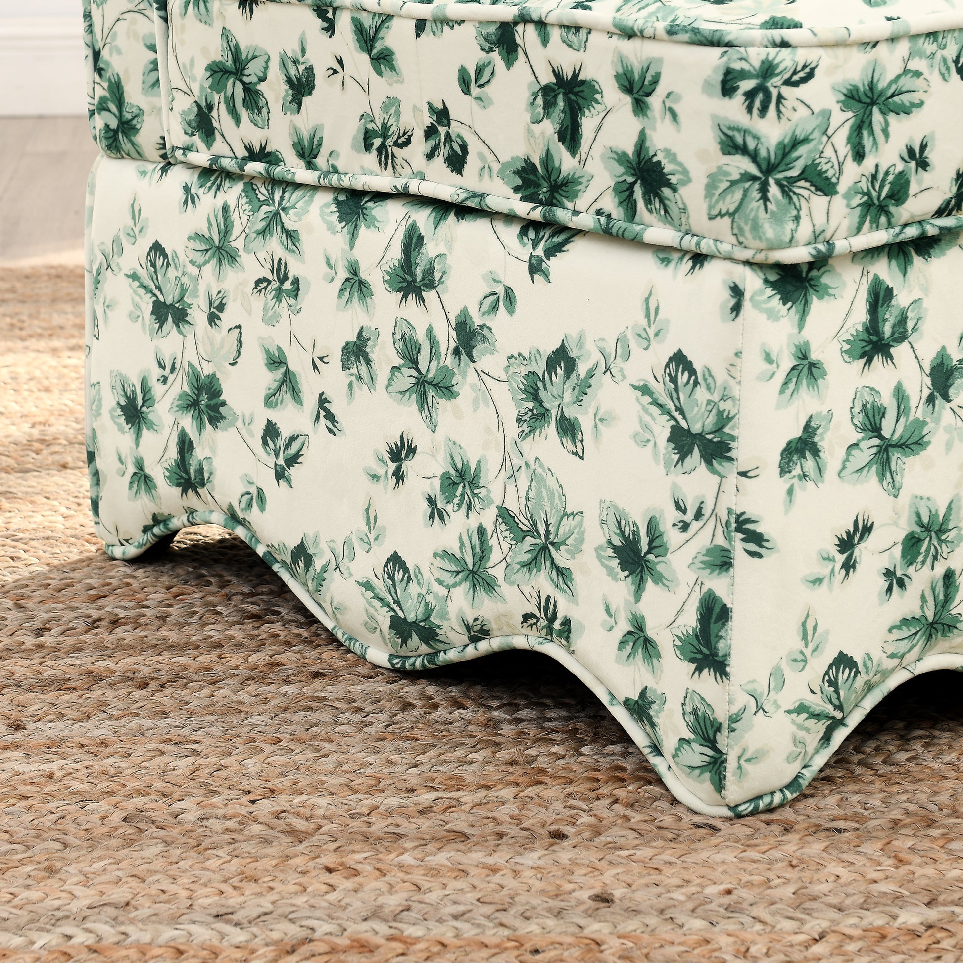 Elegant cream ottoman with a bold green leaf pattern complementing rustic jute rug