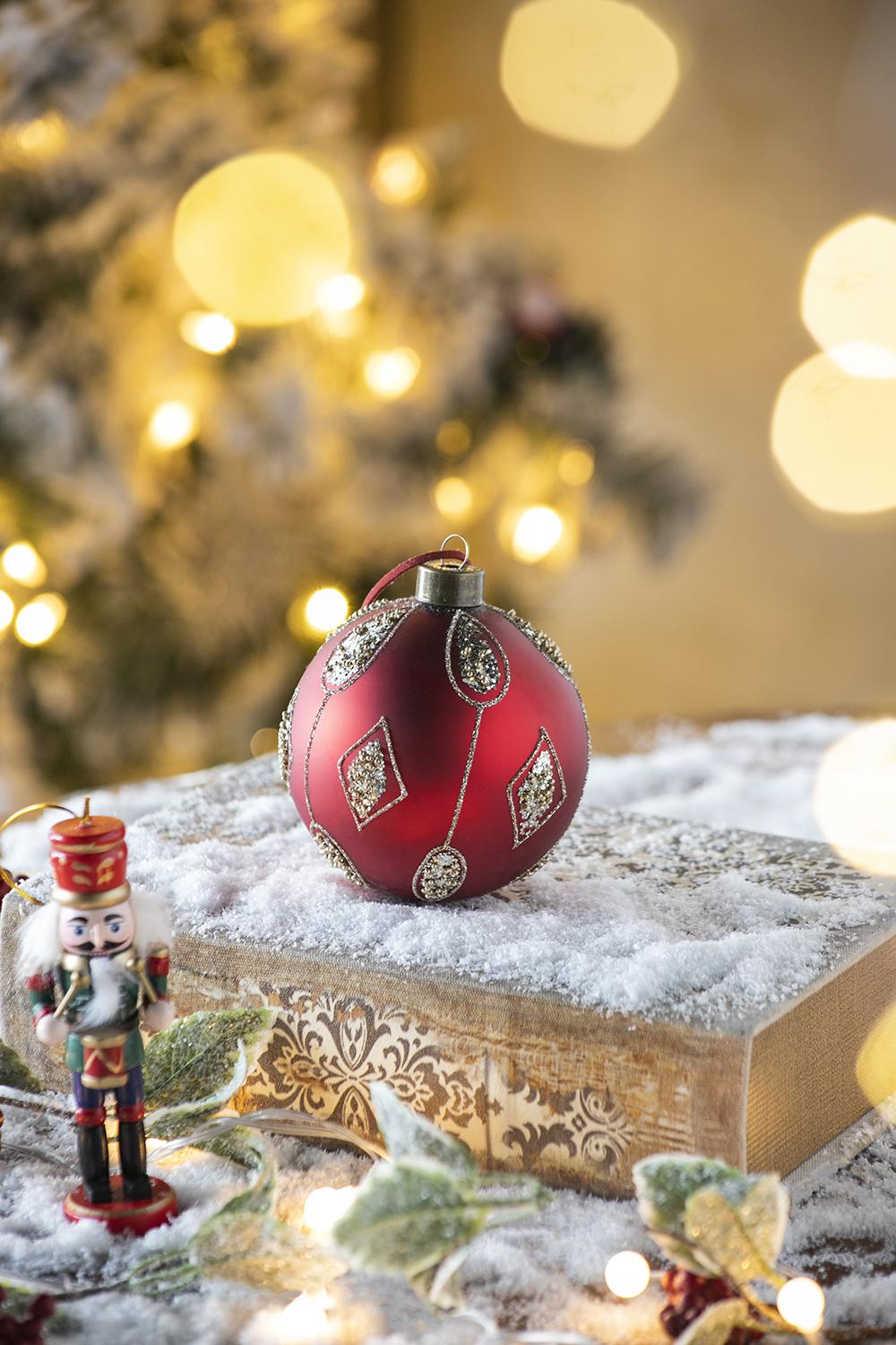 Red glittered Christmas ornament with diamond pattern placed on a decorative box