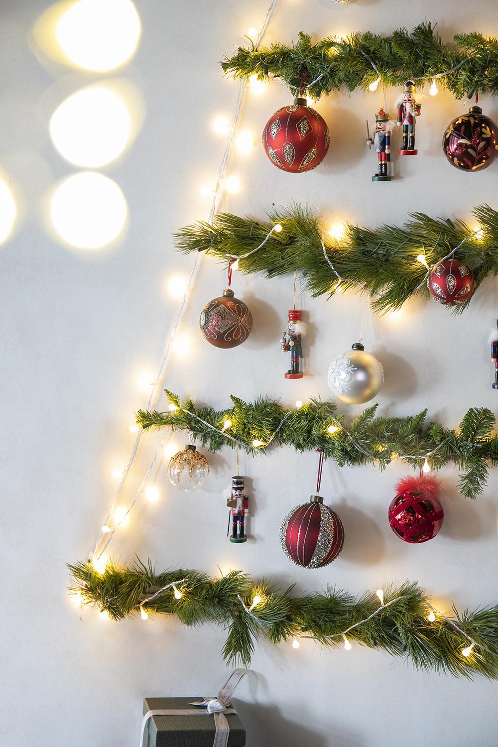 Red glitter Christmas bauble with gold leaf detail on pine garland with lights