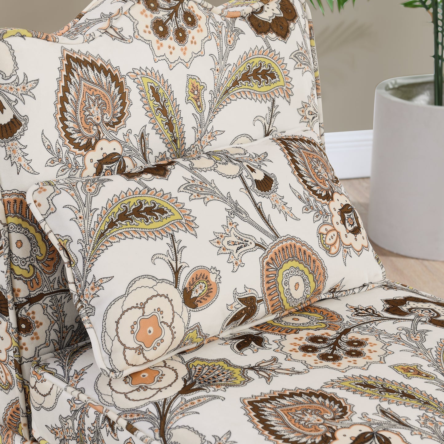 Cream throw pillow with ornate paisley pattern in brown and peach tones
