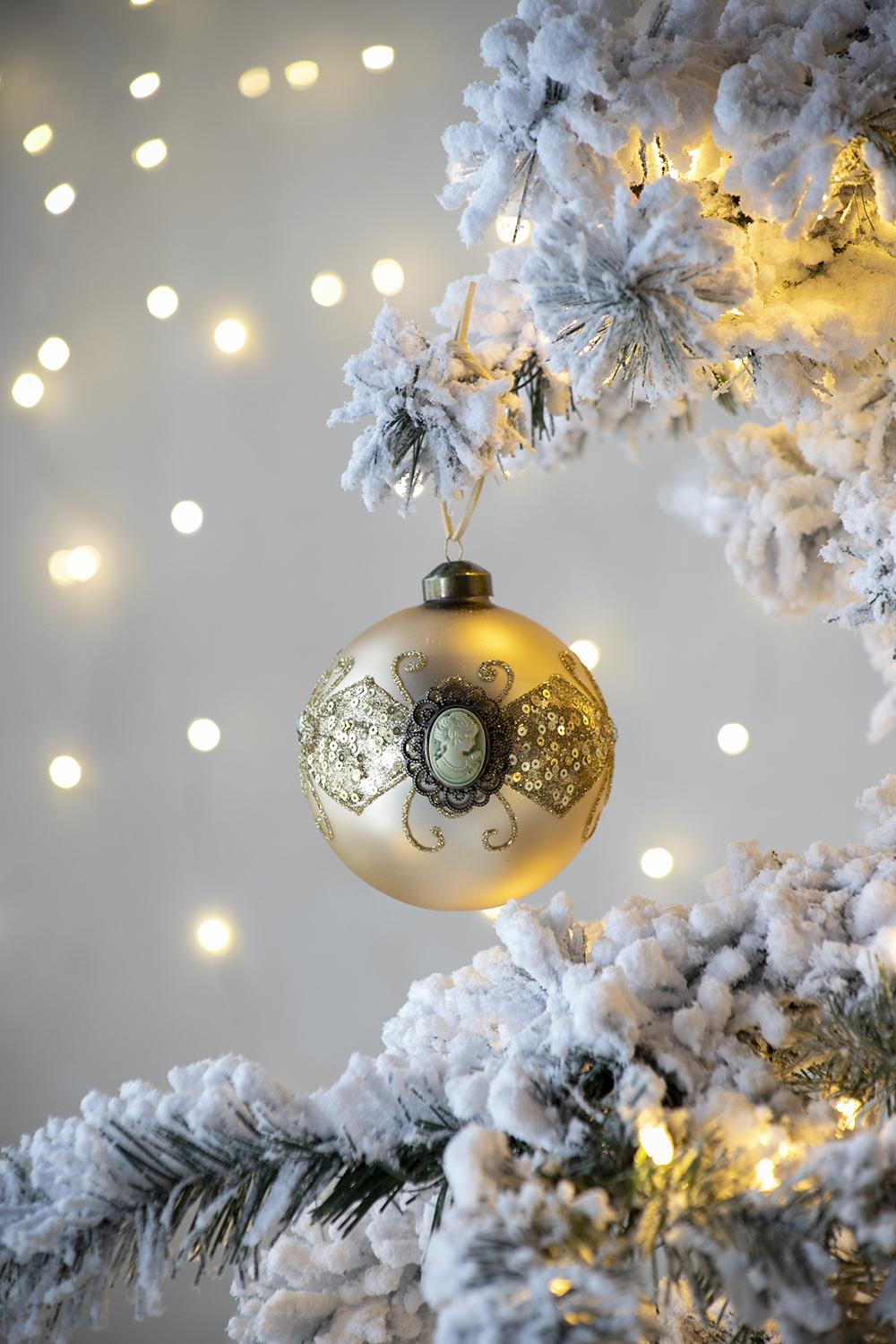 Elegant gold Christmas ornament with cameo sparkling sequins on flocked tree
