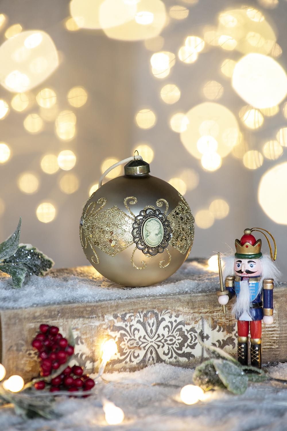 Gold ornate Christmas bauble with cameo detail accented by a nutcracker figure