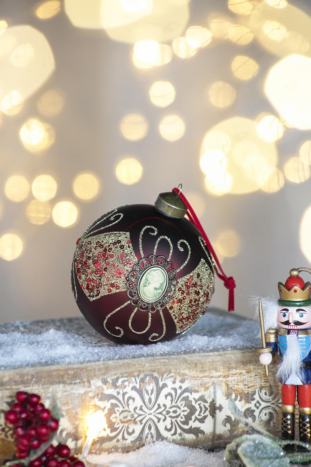 Deep red glass Christmas ornament with antique cameo embellished with gold glitter and sequins