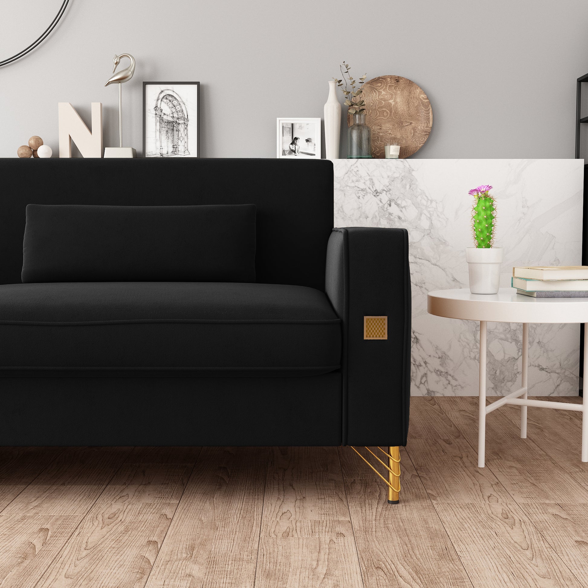Black velvet sofa with gold legs and a decorative armrest accent