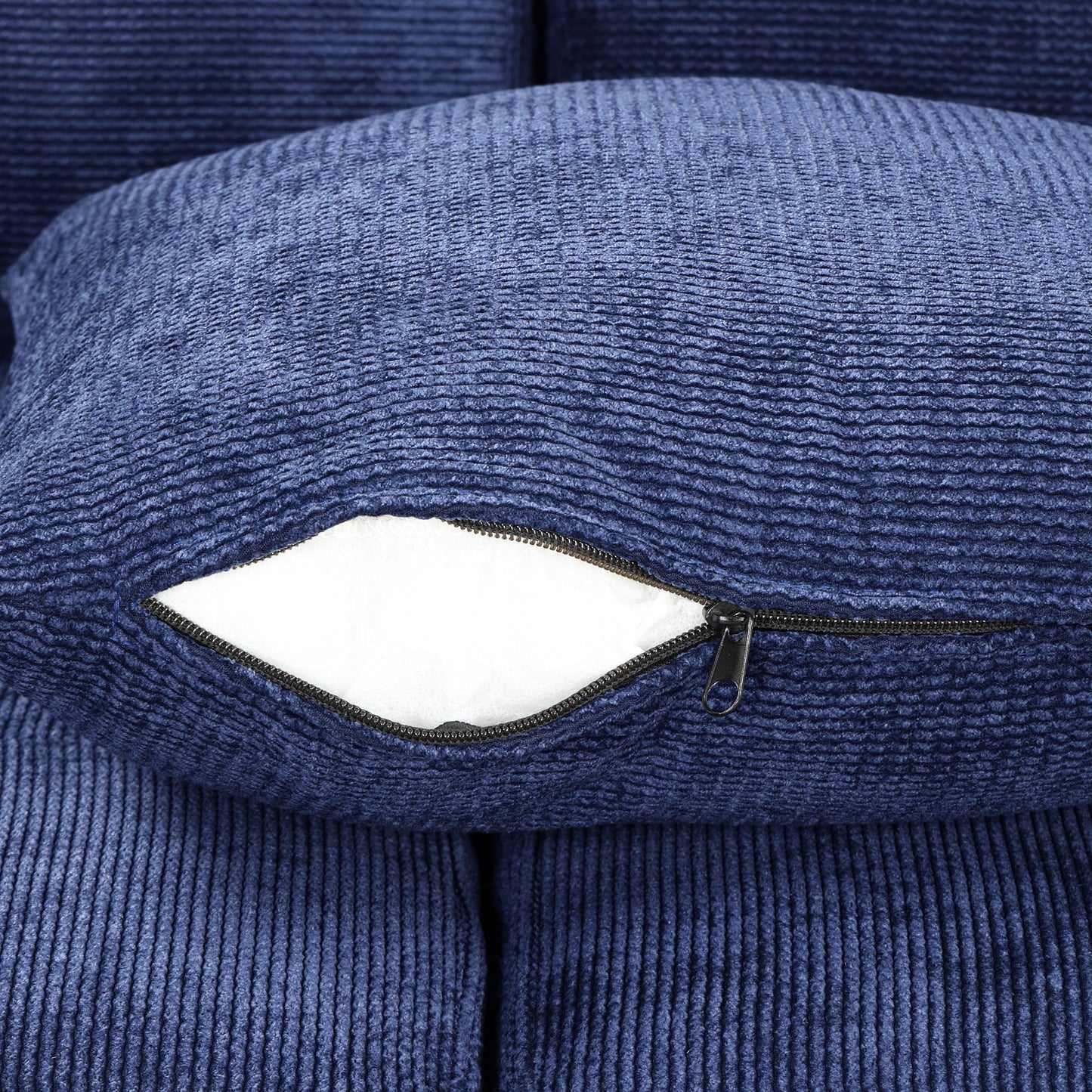 Closeup of a textured navy blue corduroy throw pillow with a partially unzipped cover