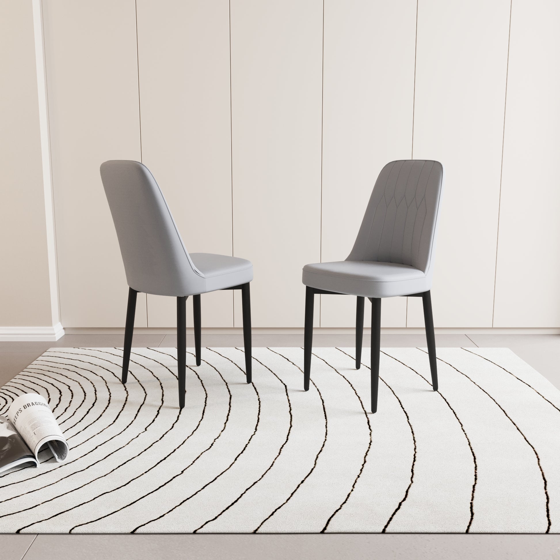 Two grey upholstered dining chairs with black legs on a black and white striped rug