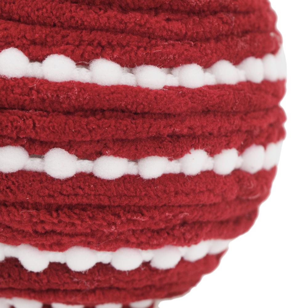 Closeup of a red knitted ball with white pompom trim festive holiday decor