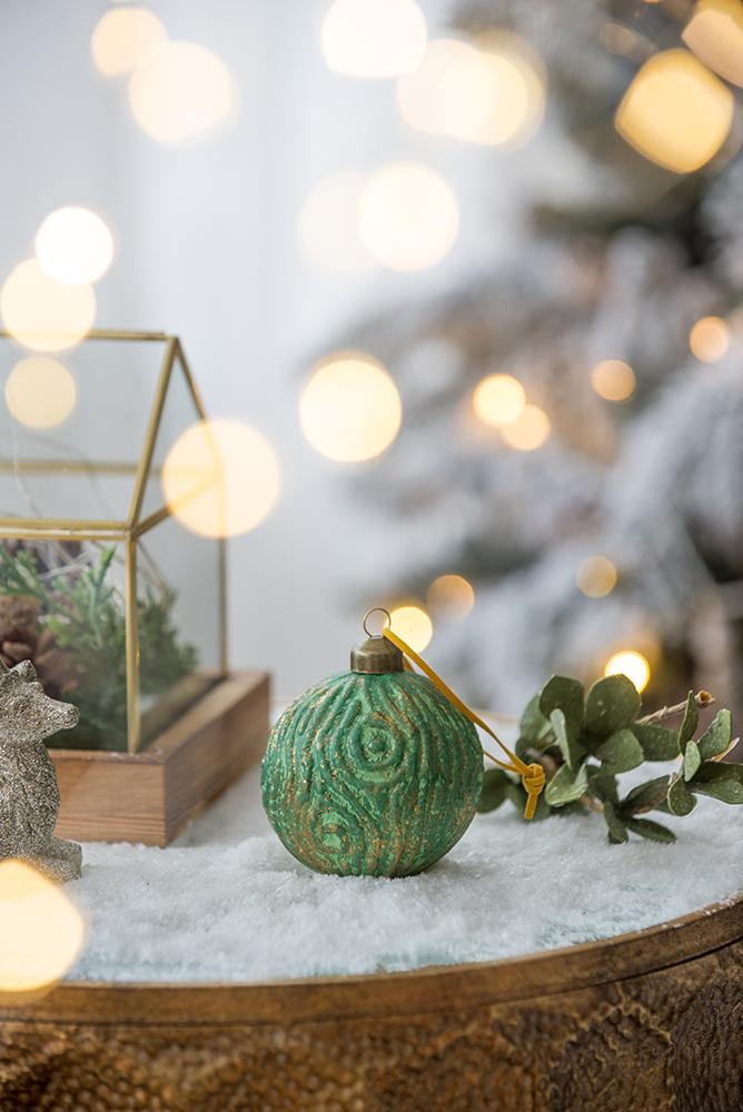 Textured green Christmas ornament with gold accents and festive lights