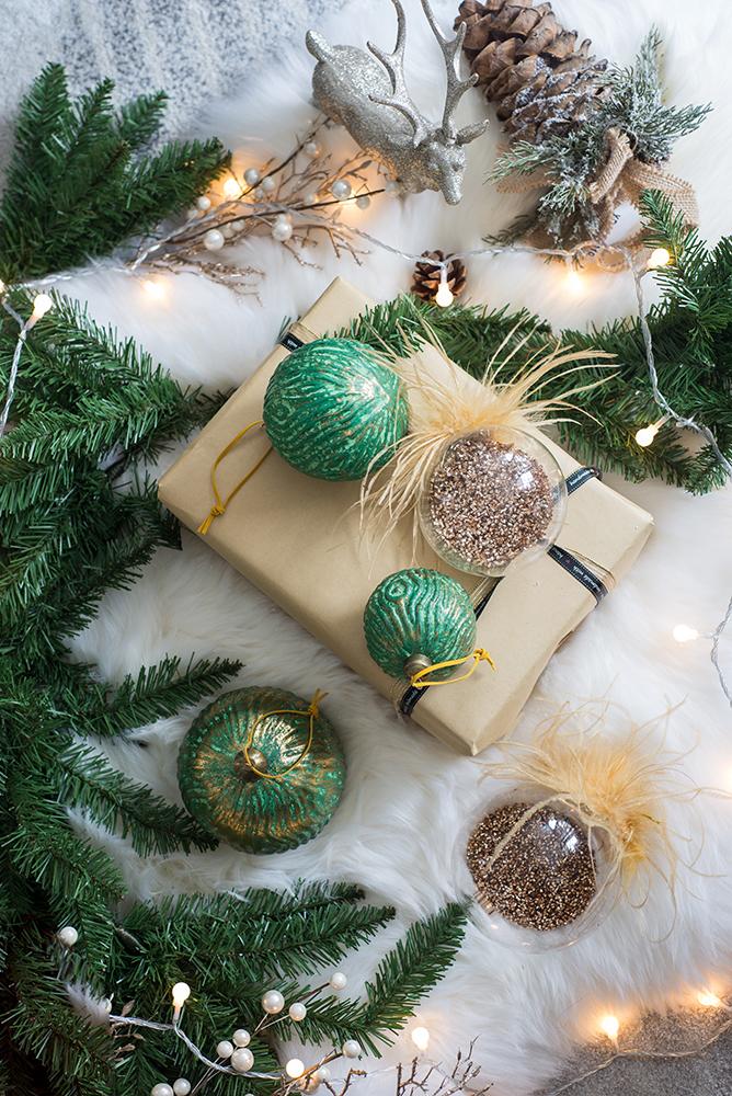 Textured green and gold Christmas ornaments with glitterfilled clear baubles nearby